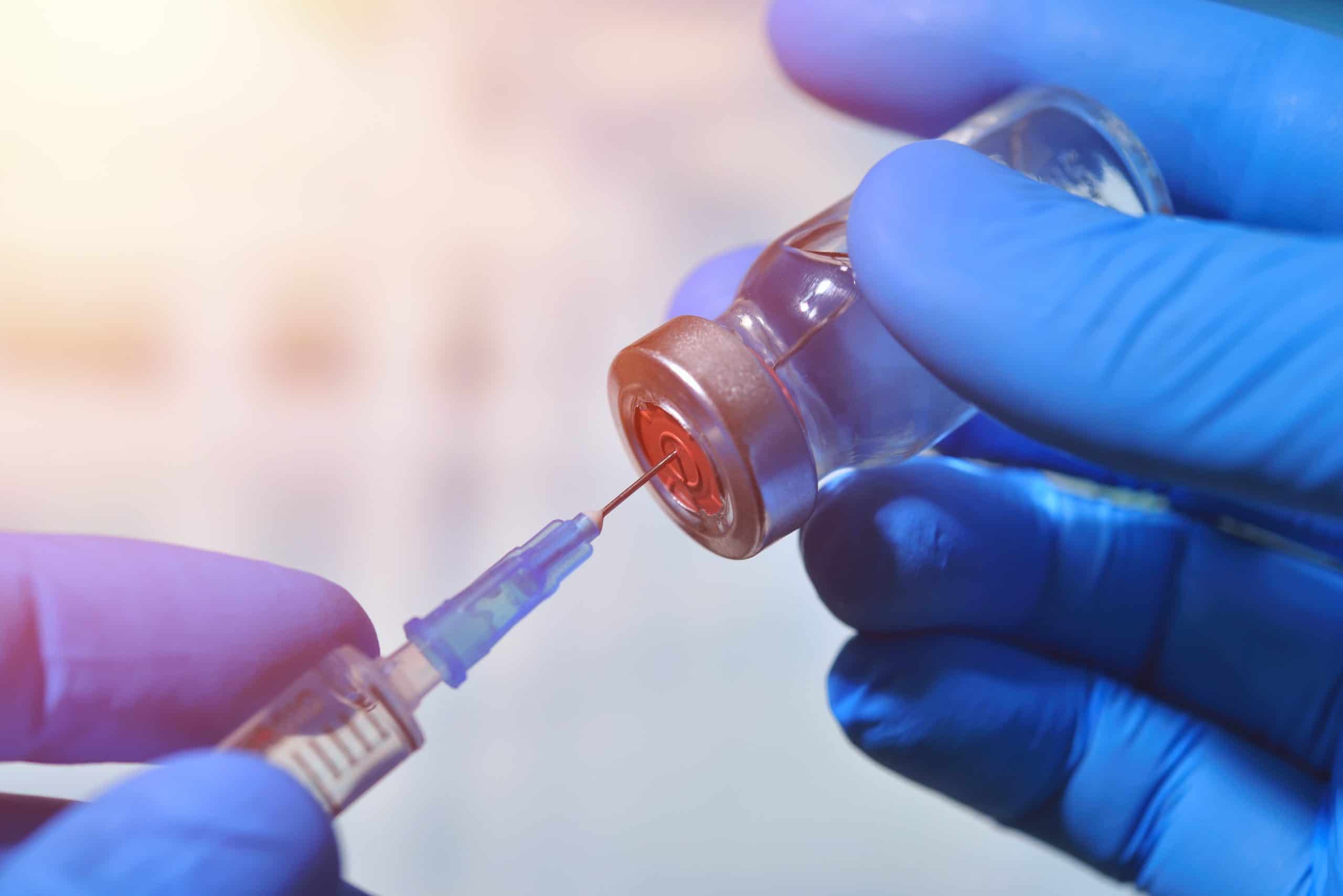 Picture of hands filling a seringue from a vaccine vial